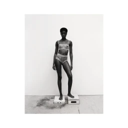 Black and white studio portrait of a Black woman wearing patterned underwear standing on two small blocks