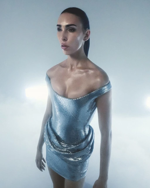 Elegant adult woman in a silver metallic off-the-shoulder dress with cinched waist, posing against a white background with studio lighting.