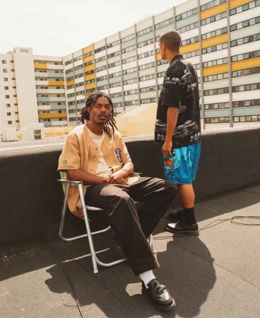 Two men on a rooftop with a large residential apartment building in the background, photographed by Arturo Torres.