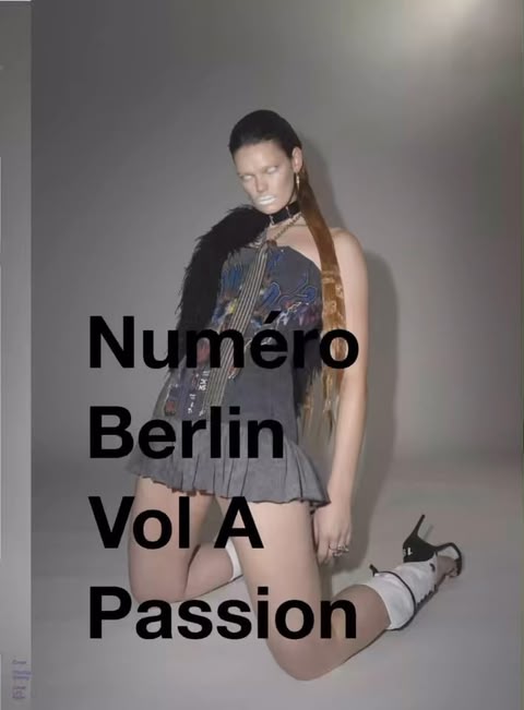 Fashion photo of a woman kneeling in heels, wearing a dark strapless top, grey skirt, and fur stole. She's posed against a grey background.