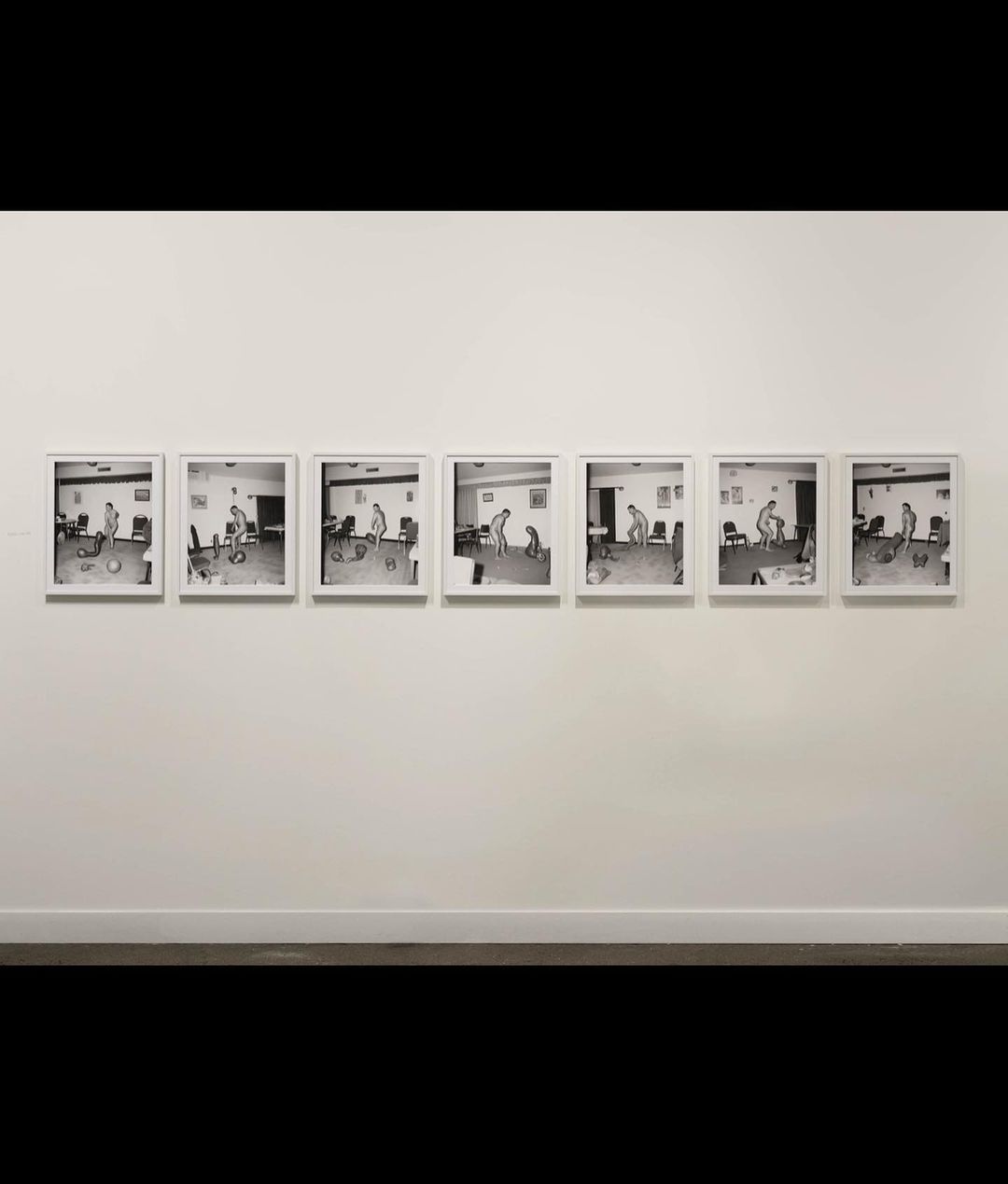 Monochrome sequential photography art on gallery wall featuring an individual in various poses in an institutional-style indoor setting.