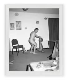 Monochrome photograph by Asger Carlsen featuring a nude man standing in an interior space near an abstract sculptural object.