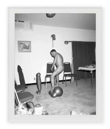 Black and white photograph of a man standing on distorted inflatable objects in a room