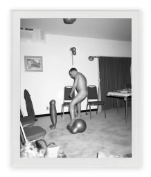 Black and white photograph of a man standing on distorted inflatable objects in a room