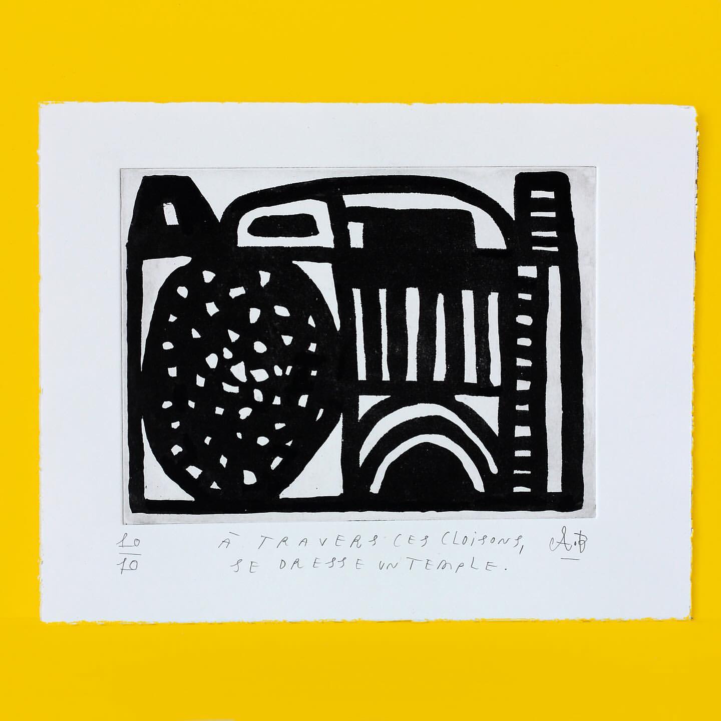 Abstract art print in black and white with geometric shapes, displayed on a yellow background. The print has hand-written text.