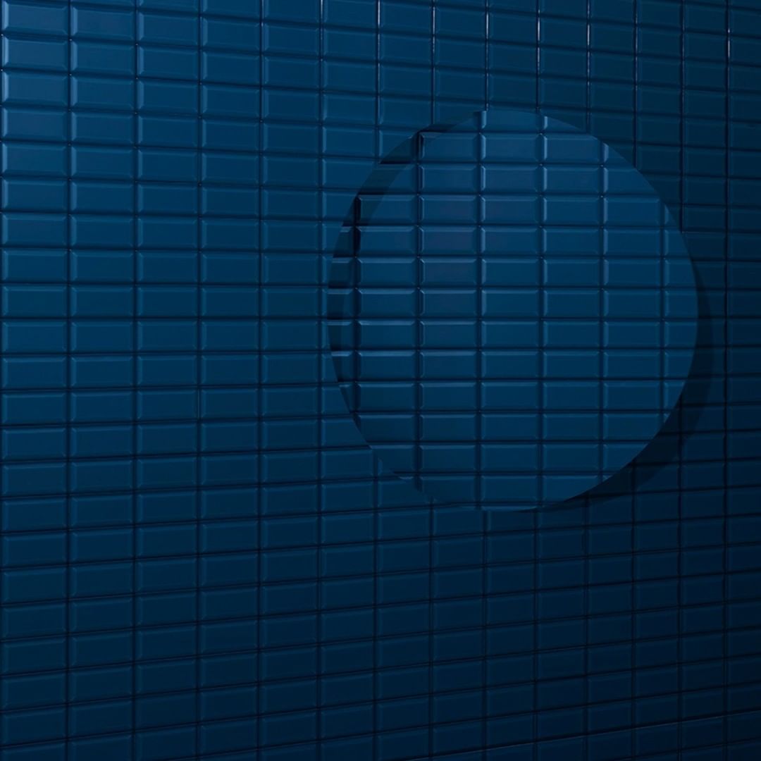 Abstract image of a blue tiled wall with a smooth, recessed circular shape, creating a modern, minimalist aesthetic.