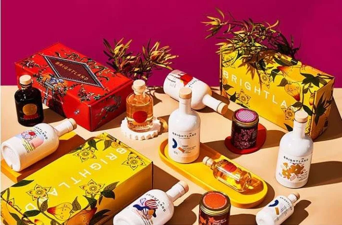 Brightland product display featuring olive oils, vinegars, and colorful packaging against a bright pink backdrop. Food and beverage.