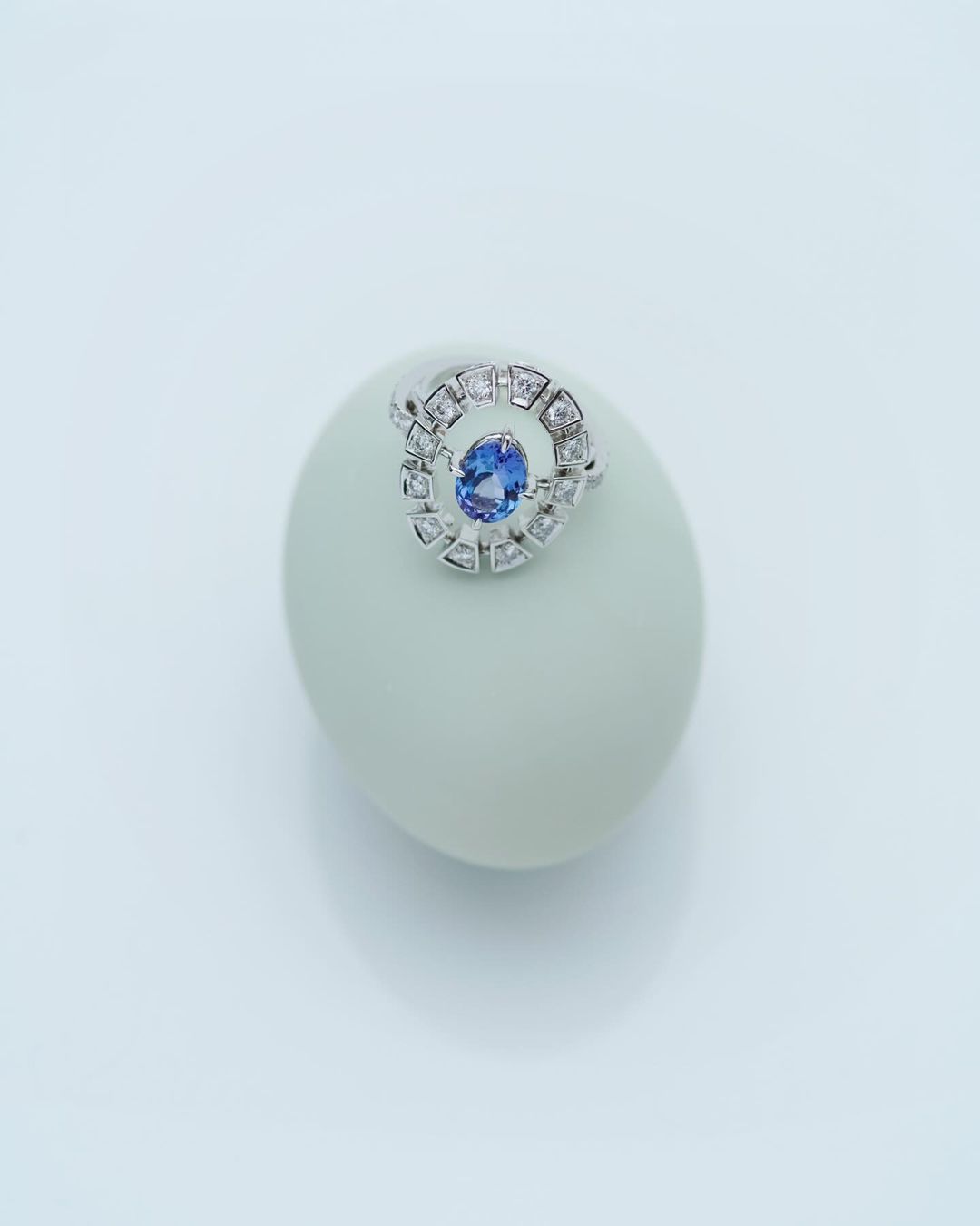 Close-up studio shot of a ring with a blue gemstone set on a white object against a bright white background, creating a clean aesthetic.