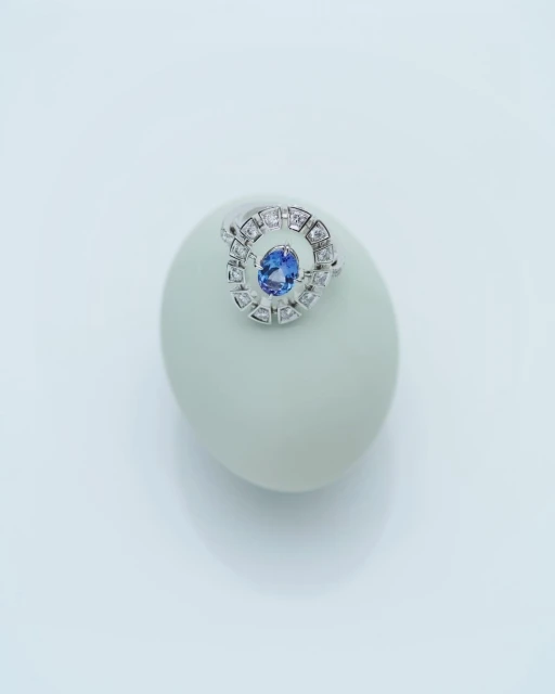 Close-up studio shot of a ring with a blue gemstone set on a white object against a bright white background, creating a clean aesthetic.