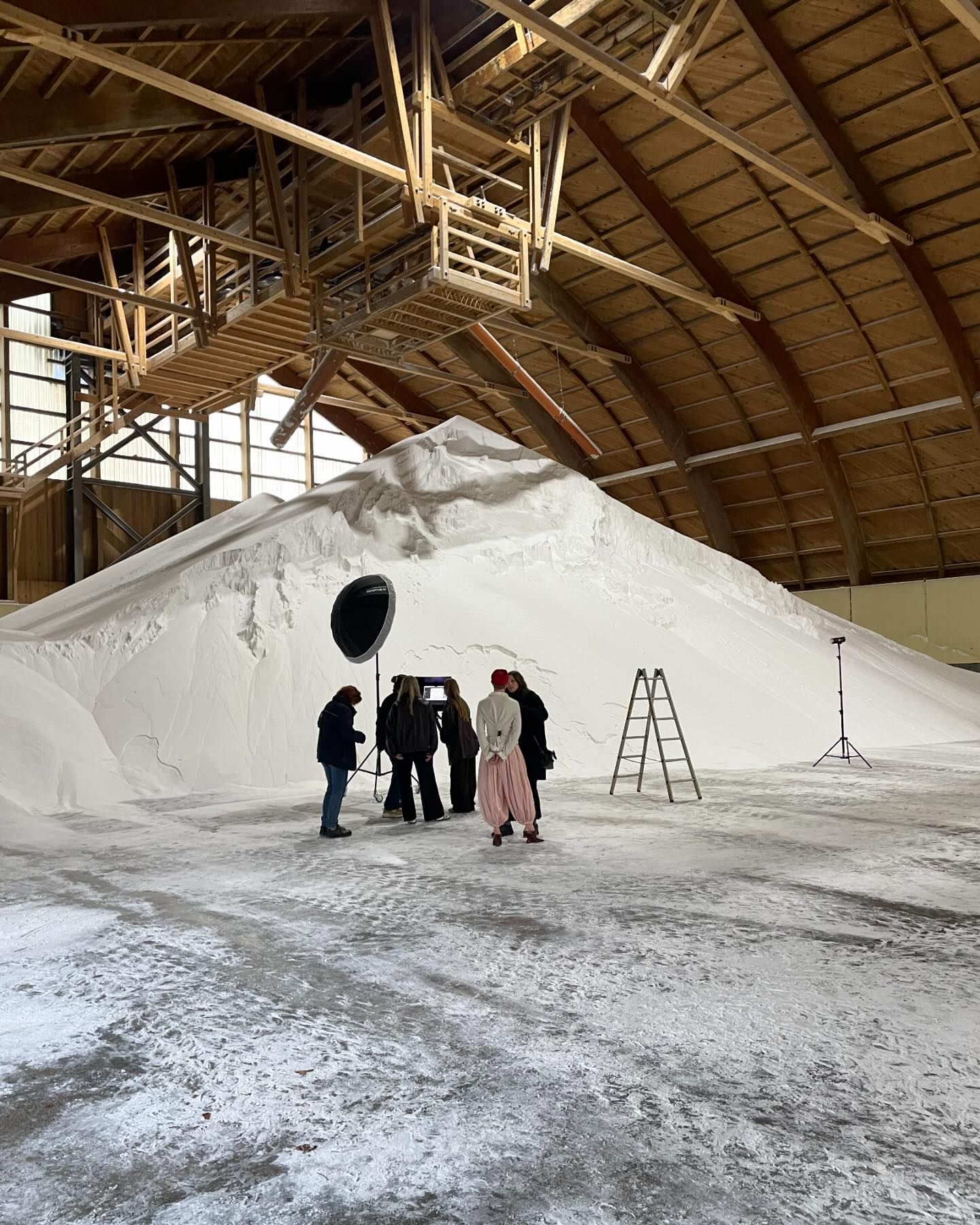 Filming at indoor location with a large white pile. Several people are setting up filming equipment and preparing to film a scene.