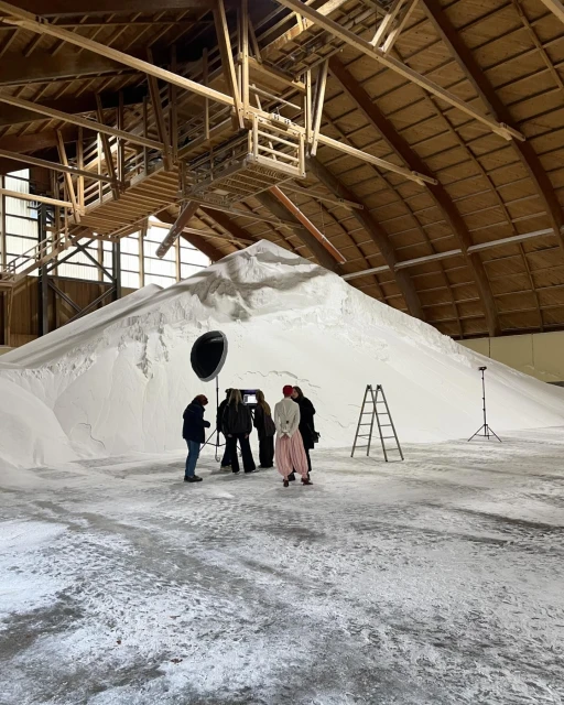 Filming at indoor location with a large white pile. Several people are setting up filming equipment and preparing to film a scene.