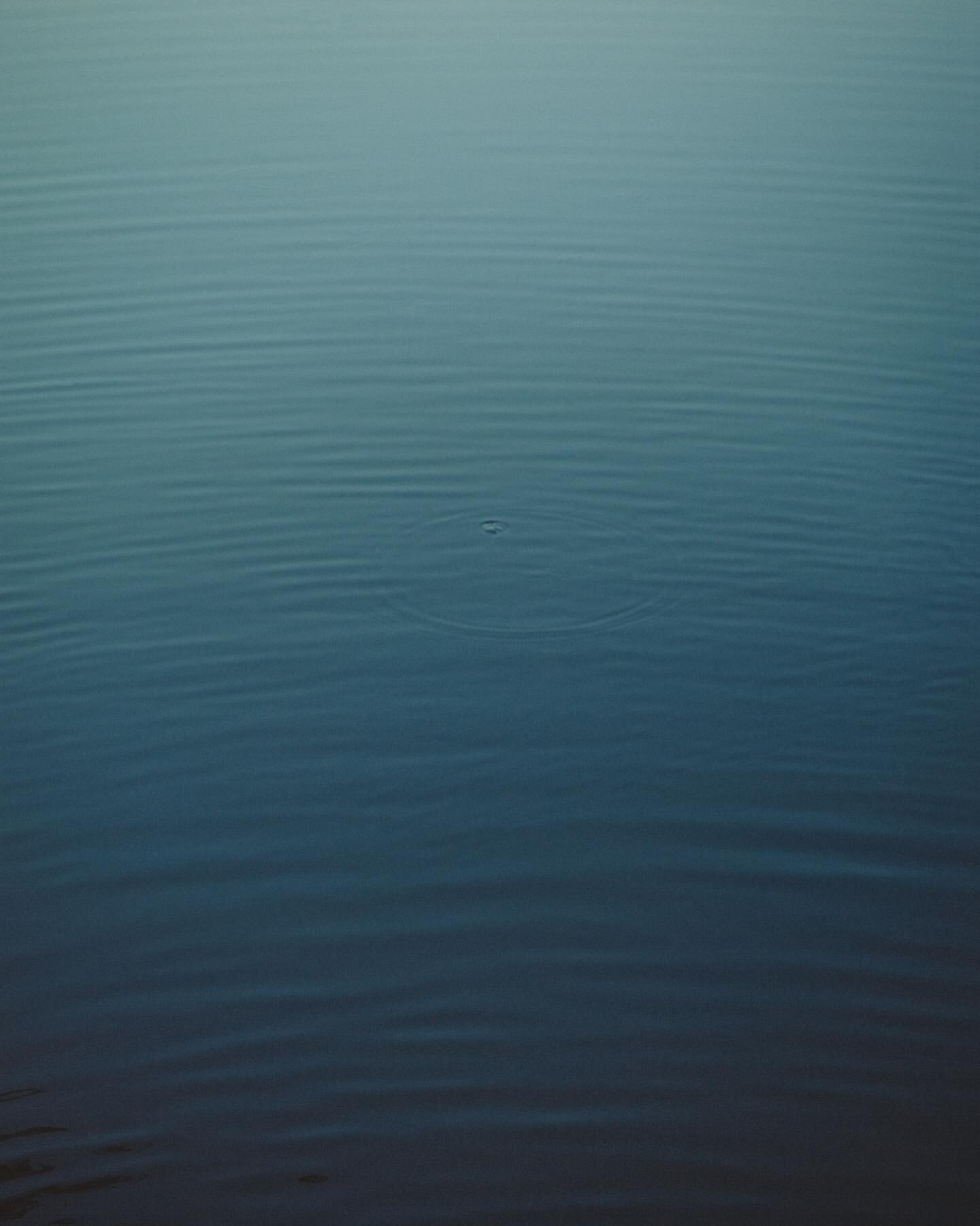 Calm, still body of water showing subtle wave patterns with a gradient of blue shades from dark to light, emphasizing tranquility.