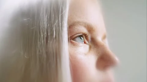 Extreme close-up portrait of a woman with white hair and blue eyes directed by Aurora Panero