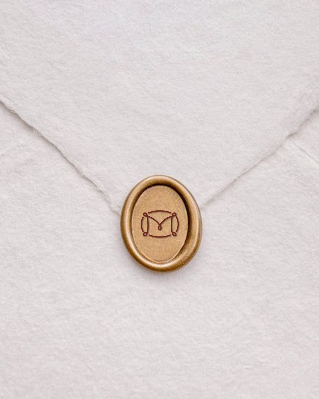 Close-up studio shot of a wax seal with an 'M' design on a white envelope, creating a sophisticated and personalized stationery detail.