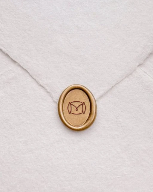 Close-up studio shot of a wax seal with an 'M' design on a white envelope, creating a sophisticated and personalized stationery detail.