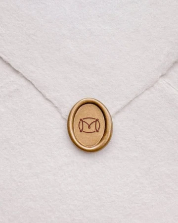Close-up studio shot of a wax seal with an 'M' design on a white envelope, creating a sophisticated and personalized stationery detail.