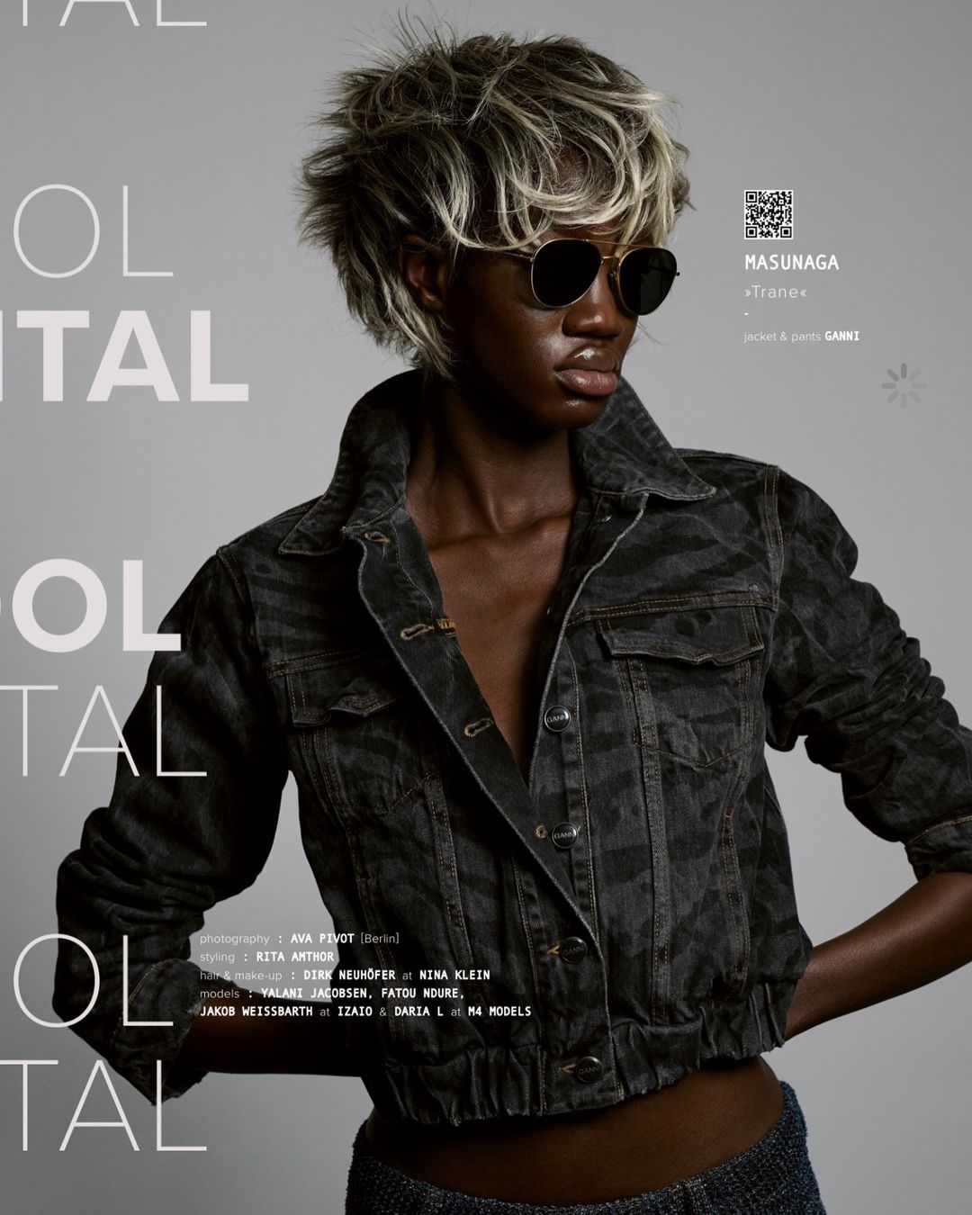 Fashion shot of a Black female model with blonde hair wearing round sunglasses and a black jean jacket against a grey background.