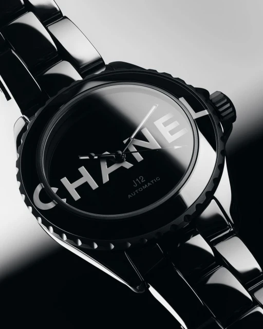 Closeup of a black Chanel J12 automatic watch featuring a ceramic bracelet and bezel, emphasizing luxury and modern design.