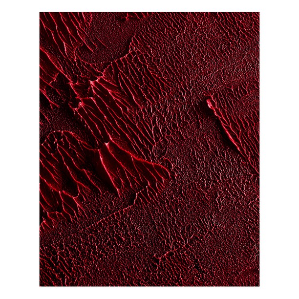 Close-up of abstract art featuring textured, glossy red paint, creating a visually striking and dynamic surface for artistic projects.