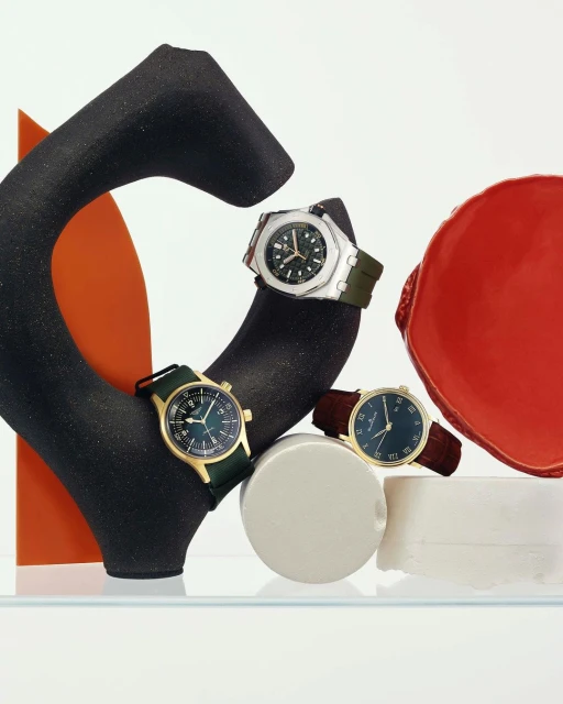 Three wristwatches are displayed on abstract geometric pedestals against a stark white backdrop, showcasing their unique designs and styles.