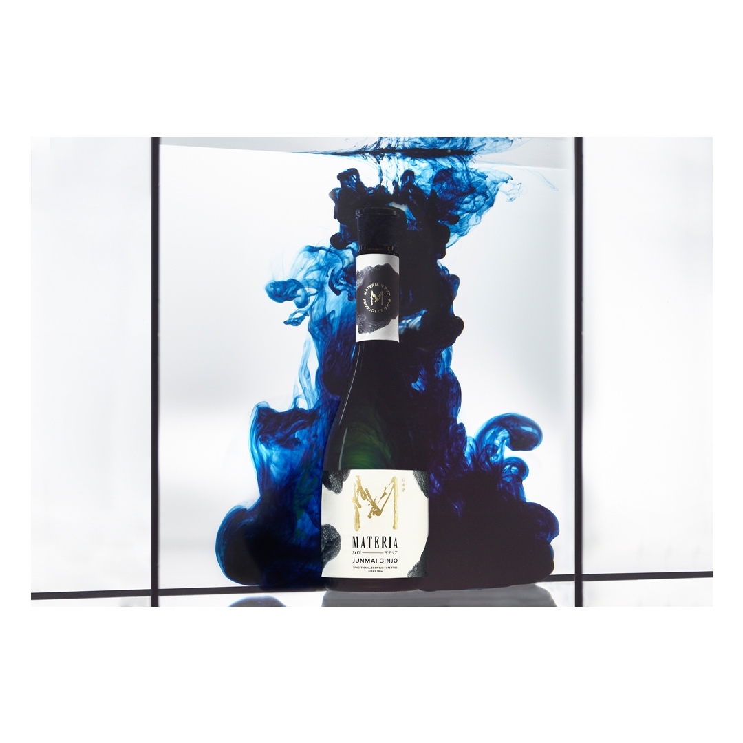 Studio shot of a wine bottle engulfed in swirling blue liquid, set against a minimalist grid backdrop, showcasing artistic food and beverage product photography.
