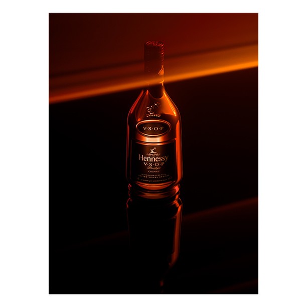 Elegant cognac bottle on reflective surface with a sleek design, warm gradient lighting, and minimalist composition for visual appeal.