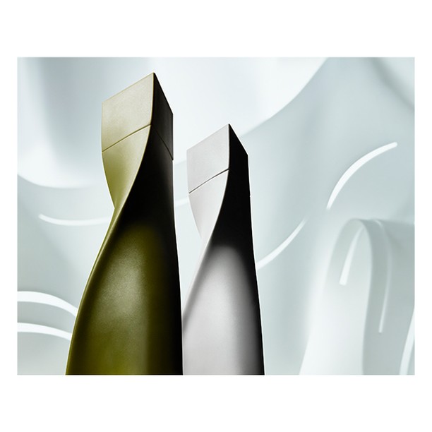 Abstract product shot featuring two uniquely designed bottles, showcasing smooth surfaces and geometric tops against a soft, curved background.