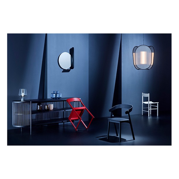 Interior design showcasing a blue wall, modern lighting fixtures, a mirror, a buffet, and an assortment of stylish chairs in various colors.