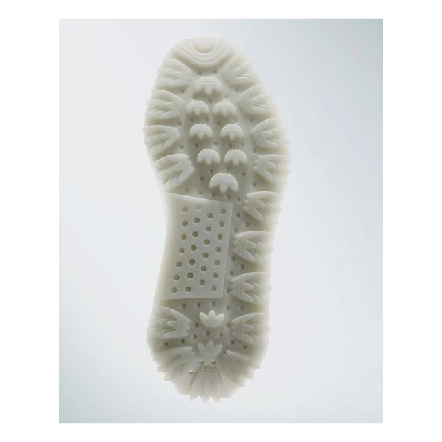 Close-up studio shot of the textured sole of a white shoe with circular and ridge patterns, highlighting the design and grip.