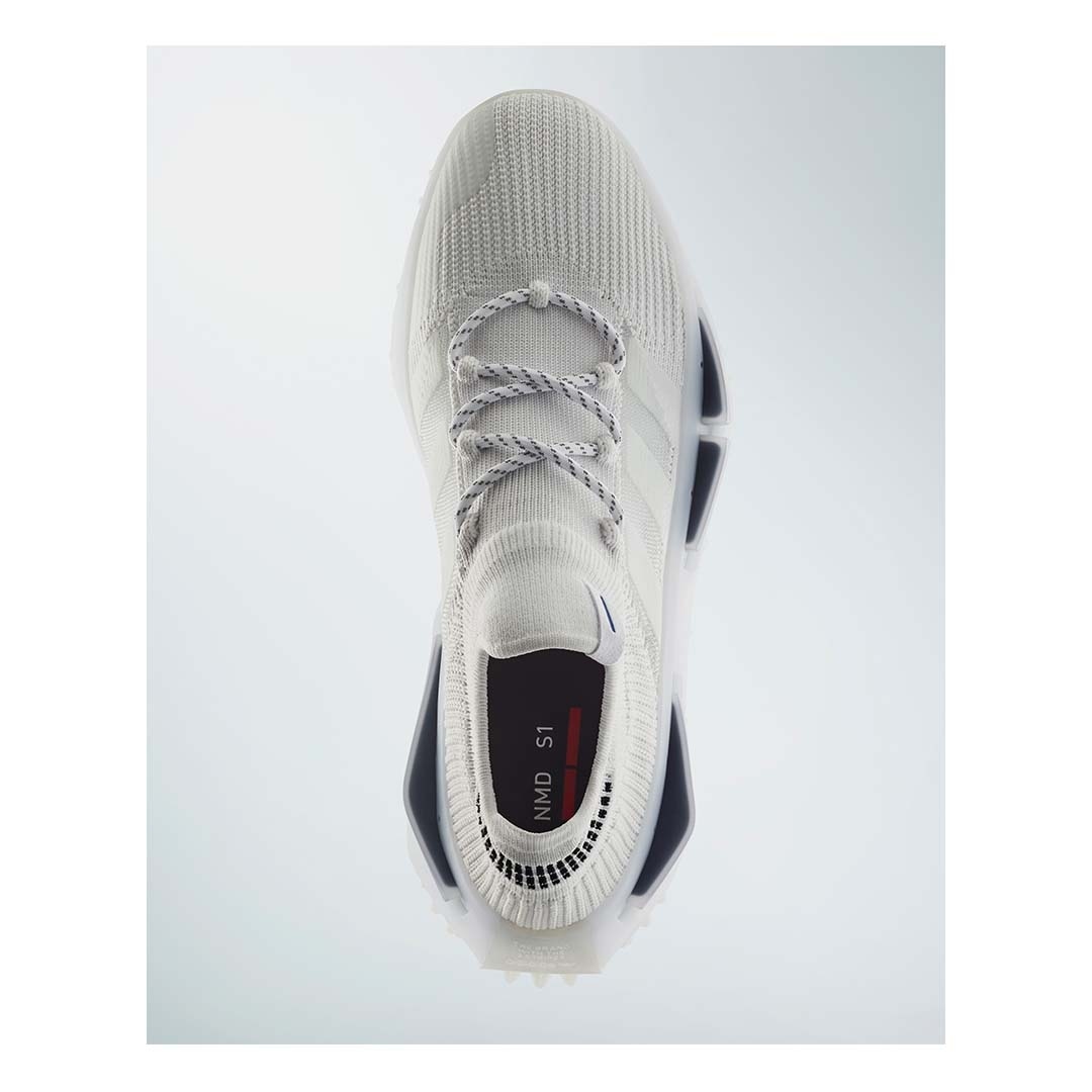 Studio shot of an Adidas NMD S1 sneaker featuring a sock-like construction, rope laces, and a white color scheme against a white background.