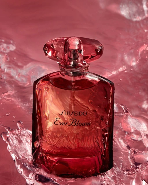 Shiseido Ever Bloom perfume bottle stands prominently amidst a captivating splash of red-tinted water, creating a dynamic beauty shot.