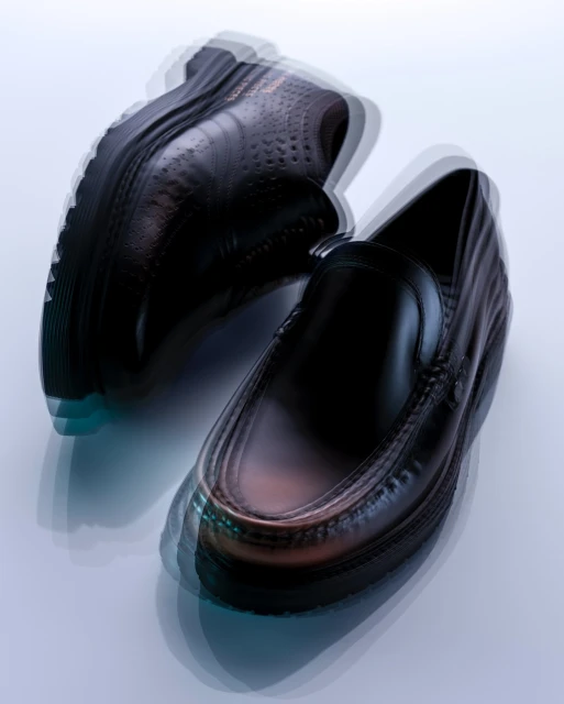 Studio shot of a pair of black leather men's loafers on a seamless background with intentional motion blur and a soft, cool color palette.