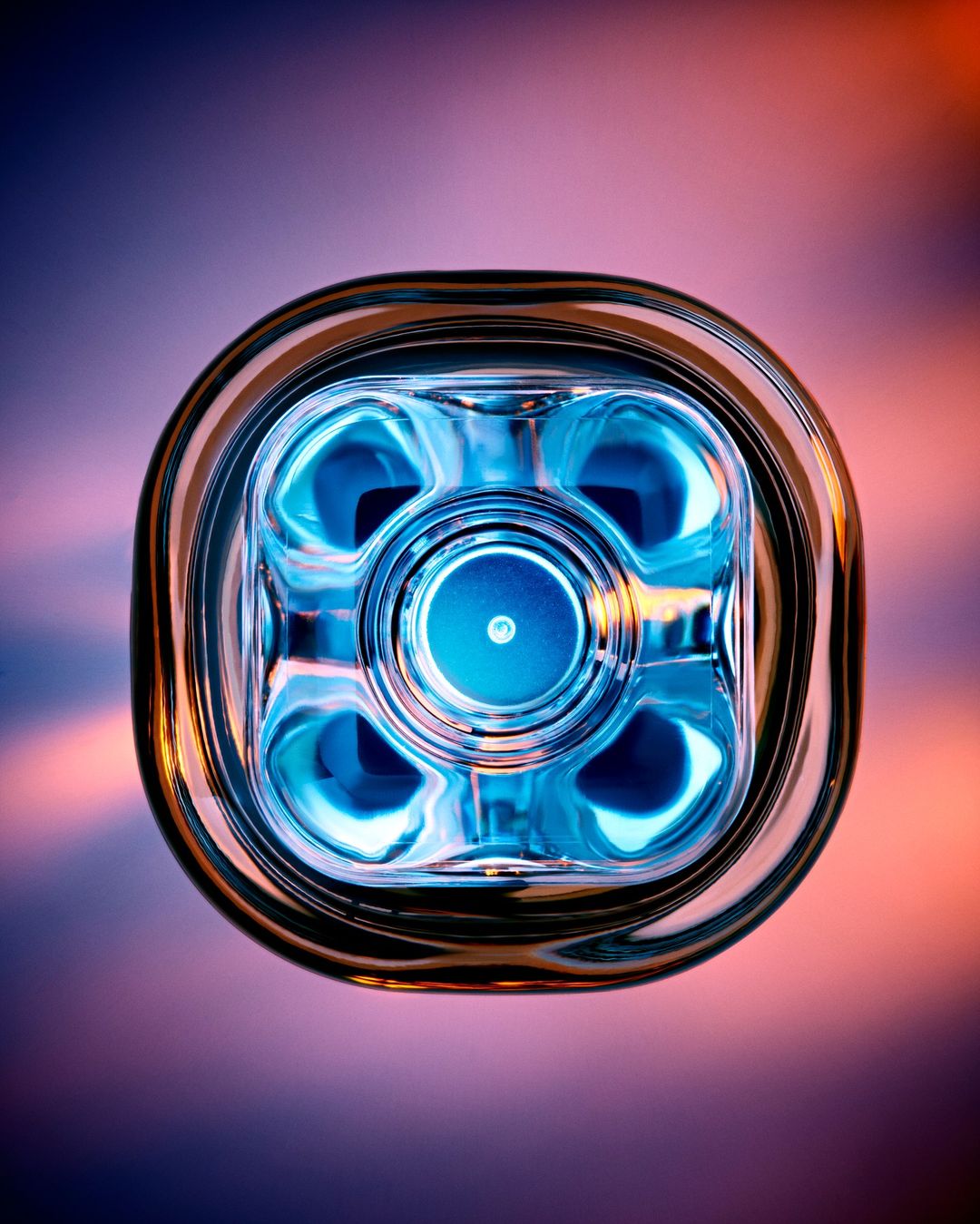 Close-up shot of a clear glass bottle with a blue liquid inside, highlighted by diffused orange and purple lighting, casting subtle shadows.