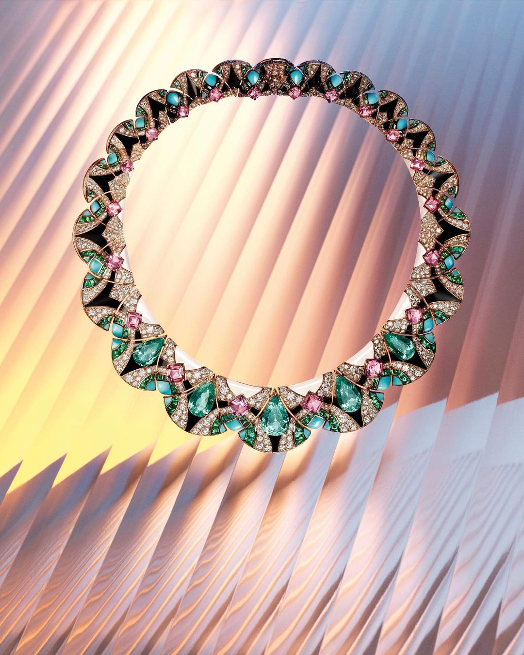 Elegant necklace featuring green, pink, and turquoise stones, set against a textured gold and white background. Jewelry fashion accessory.