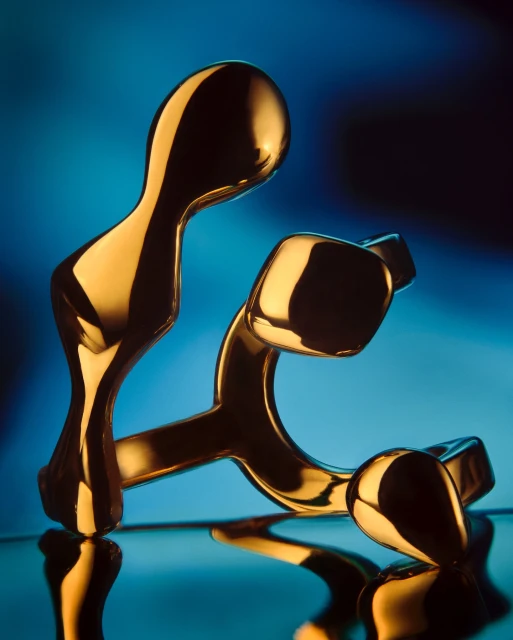 Abstract golden sculpture on a reflective surface against a gradient blue background, showcasing modern art and design elements.