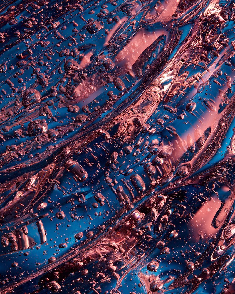 Abstract close-up of a textured surface with a flowing, liquid appearance in shades of blue and pink, creating a mesmerizing visual.