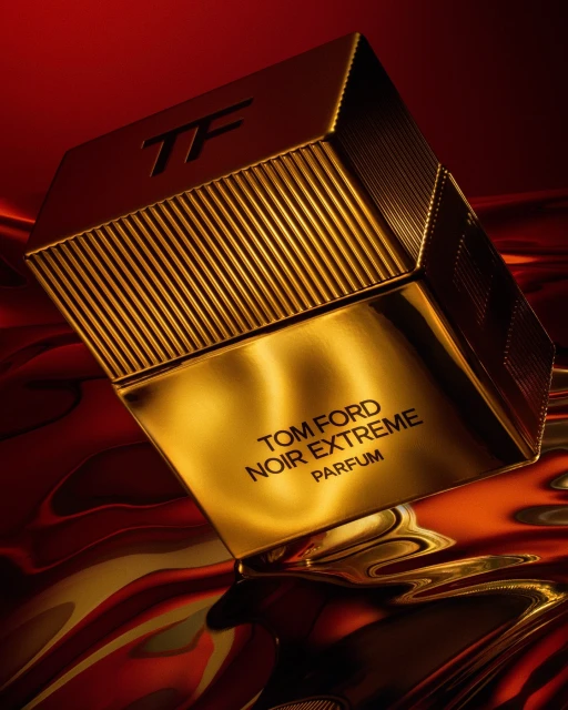 A golden bottle of Tom Ford Noir Extreme Parfum is showcased against a textured red and gold background, highlighting luxury and elegance.