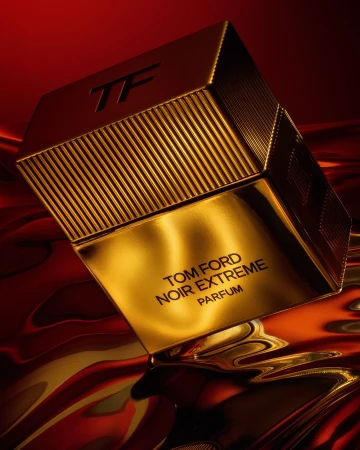 A golden bottle of Tom Ford Noir Extreme Parfum is showcased against a textured red and gold background, highlighting luxury and elegance.