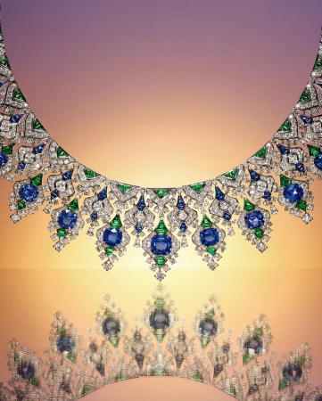 Elegant jewellery product shot featuring an ornate diamond necklace with blue and green gemstones against a gradient light-colored background.
