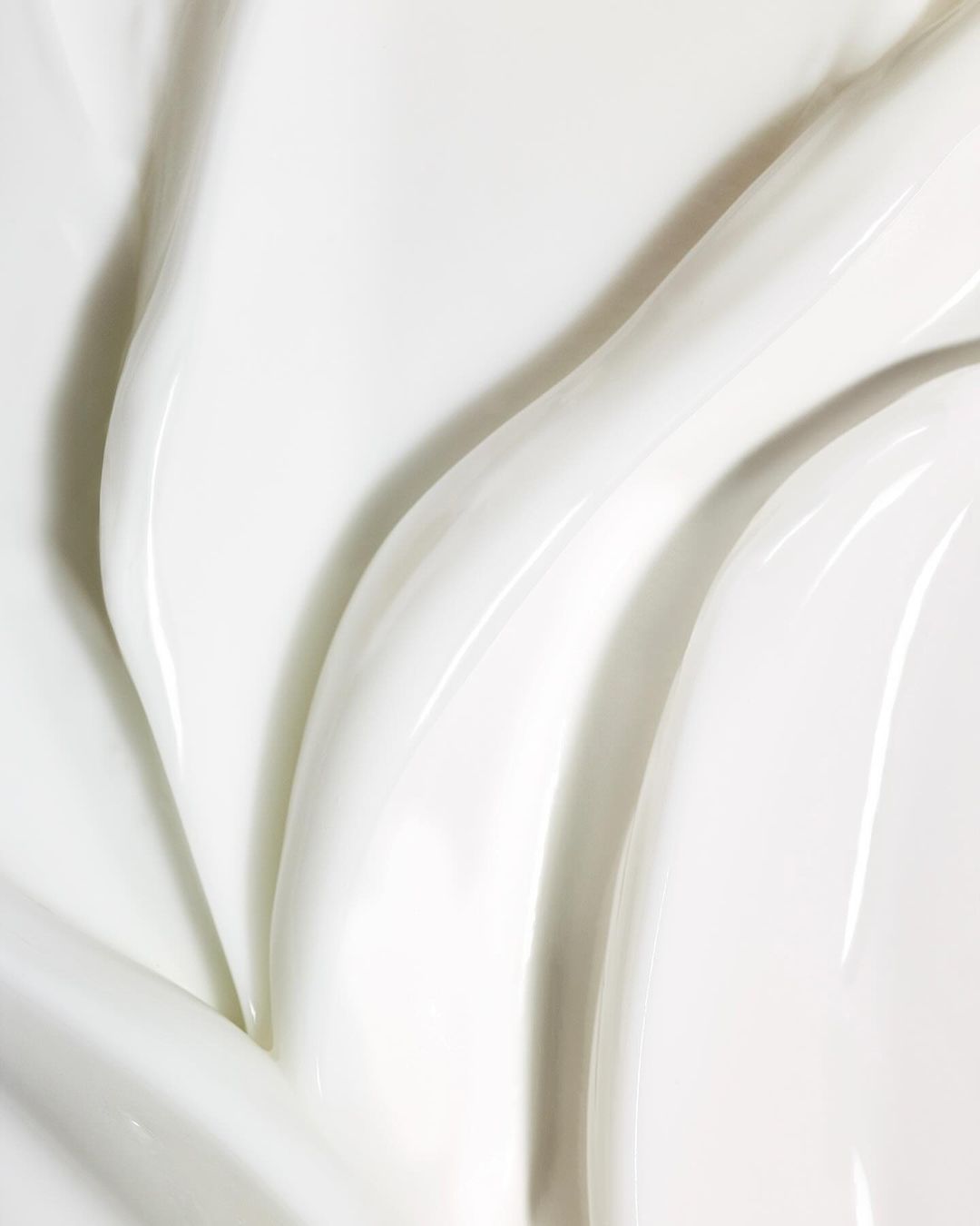Close-up view of textured white cream with glossy ridges and smooth surface, highlighting purity and rich moisturization.