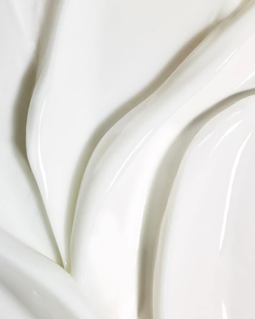 Close-up view of textured white cream with glossy ridges and smooth surface, highlighting purity and rich moisturization.