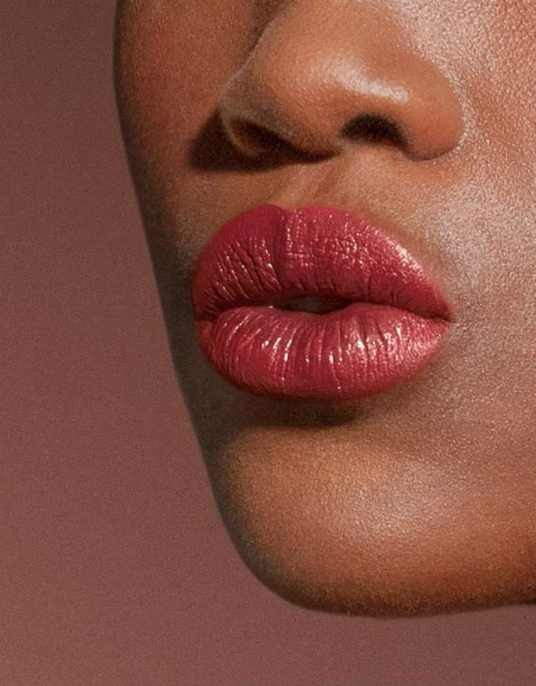 Extreme close-up of a person with deep skin wearing rich crimson lipstick, photographed by Barbara Donninelli.