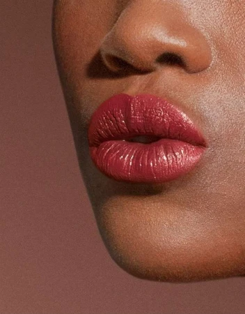 Extreme close-up of a person with deep skin wearing rich crimson lipstick, photographed by Barbara Donninelli.