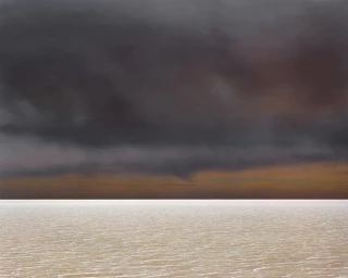 A flat expansive landscape under a heavy dark storm cloud horizon photographed by Murray Fredericks