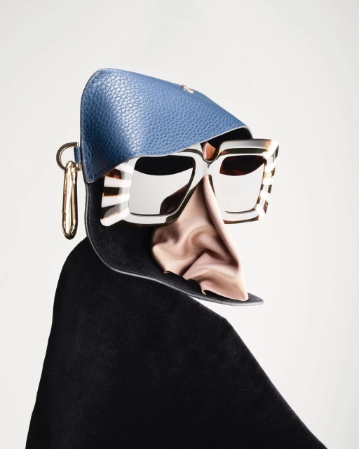Still life shot of open blue leather glasses case featuring white sunglasses with gold accents and pink silky cloth on light background.