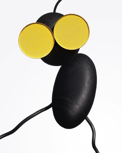 Abstract still life featuring yellow eyeshadow palettes arranged creatively on a black sculpture against a bright white background.