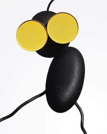 Abstract still life featuring yellow eyeshadow palettes arranged creatively on a black sculpture against a bright white background.