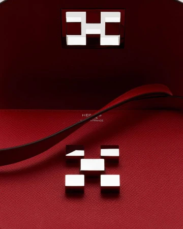 Close-up of a red leather handbag interior with silver metal hardware forming an 'H' design, showcasing luxury fashion and craftsmanship.