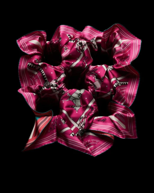 Close-up of a scrunchie made from a magenta and white patterned silk scarf, adorned with equestrian motifs, set against a stark black background.
