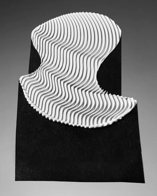 Abstract image of a white, ridged form on a black surface with a grey backdrop, creating a stark contrast and minimalist visual.